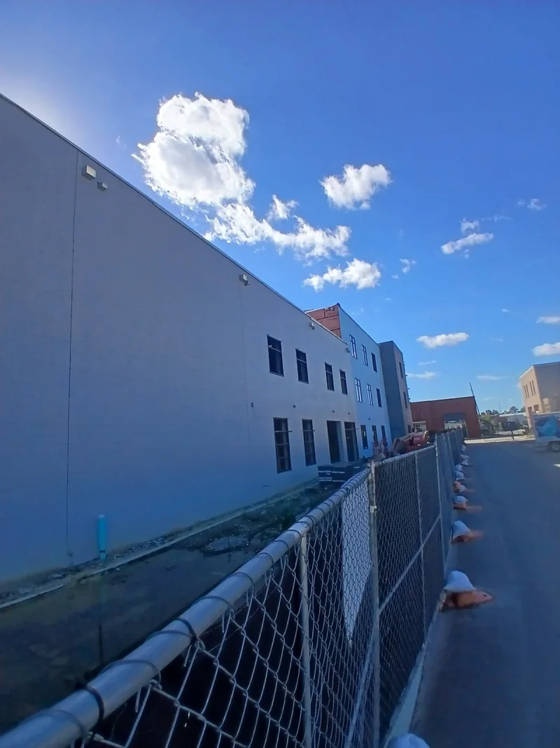 Exterior wall of a commercial building coated in an even grey-blue finish under a clear sky