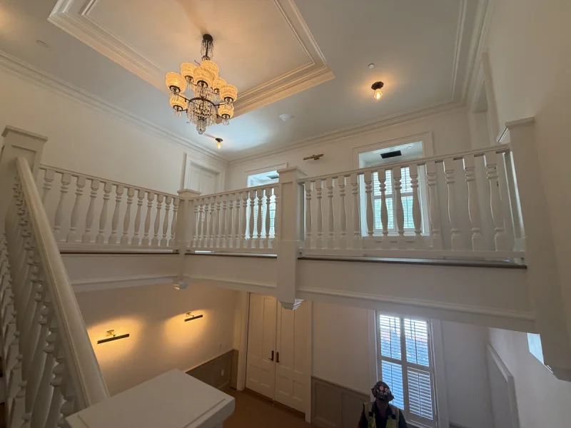 Two-story stair hall with a chandelier, white balustrade and freshly painted crown molding